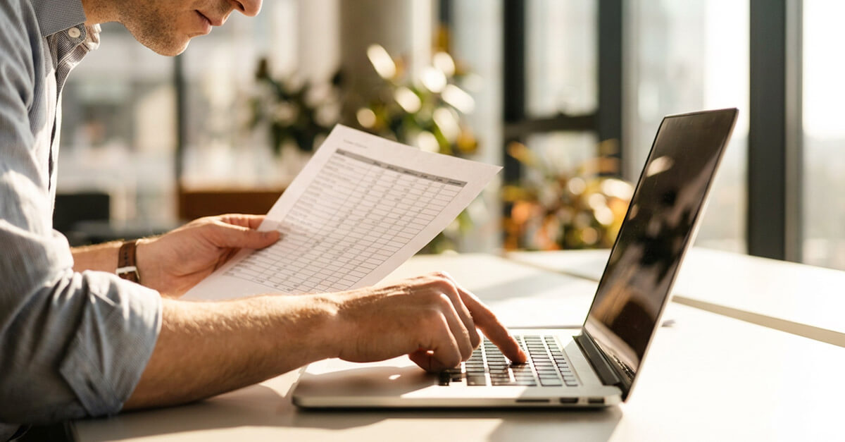 Mann überprüft Daten auf Laptop und Papier, nachhaltige Datenpflege mit der ERP-Software APplus.
